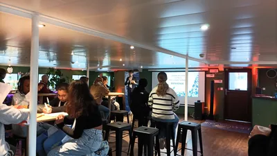 Élèves installés autour de tables hautes pour un atelier