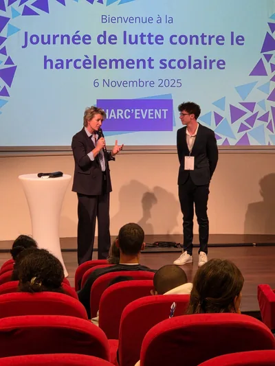Discours de bienvenue devant l'écran annonçant la journée du 6 novembre 2025